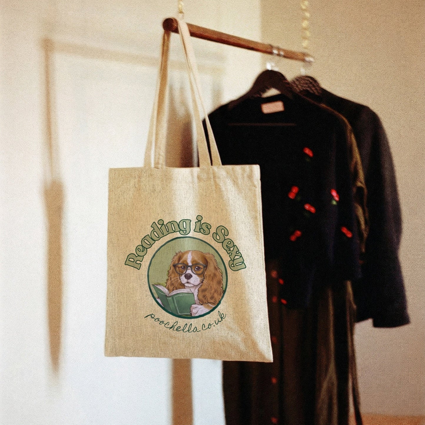 Tote bag with a dog illustration and text hanging on a rack with clothes.