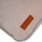 Close-up of a beige pink dog bed with a brown label on a white background