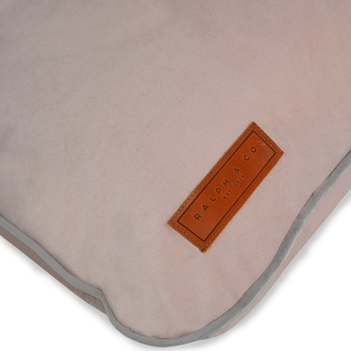 Close-up of a beige pink dog bed with a brown label on a white background