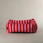 Red and pink striped pet bed on a beige background