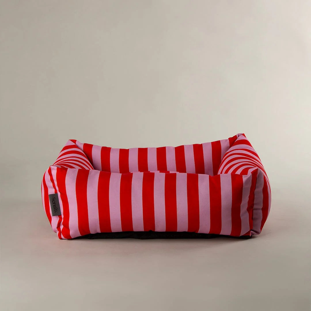 Red and pink striped pet bed on a beige background