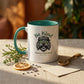 Mug with 'Be Kind Karma is Watching' text and graphic on a table with dried herbs and a spoon.