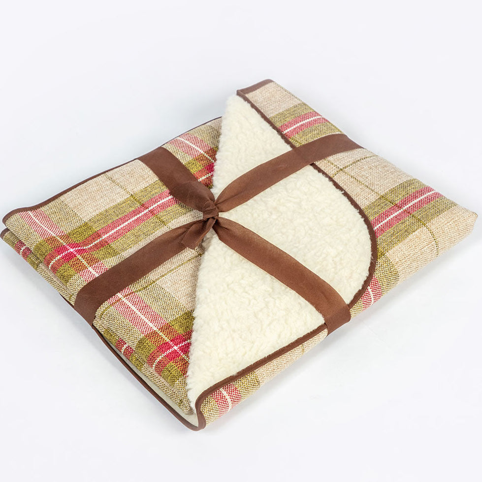 Folded plaid blanket with a brown ribbon on a white background