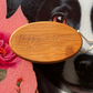 Wooden tag with 'Poppy & Basil' branding held by a dog in front of flowers
