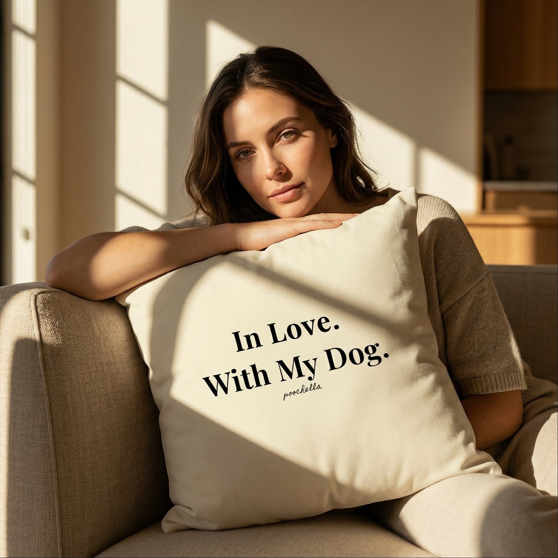 Woman holding a pillow with 'In Love. With My Dog.' text in a cozy room.