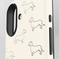 Close-up of a phone case with a cream background and black line-art illustrations of dachshunds, showing the camera cutout and side button areas.