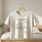 White t-shirt with dachshund graphic and text on a hanger in a bedroom setting