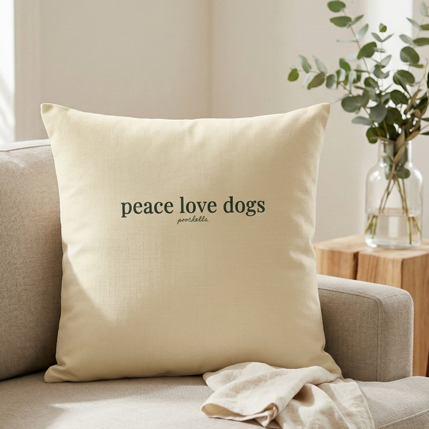 Beige pillow with 'peace love dogs' text on a beige sofa in a living room setting.