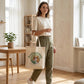 Woman holding a tote bag with a dog graphic in a bright room.