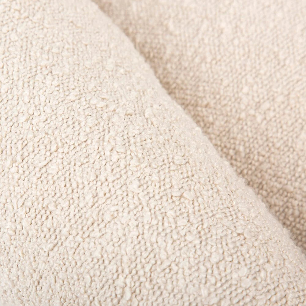 A close-up of a textured cream-colored fabric, showing a soft, looped terry cloth or bouclé texture with a diagonal fold.