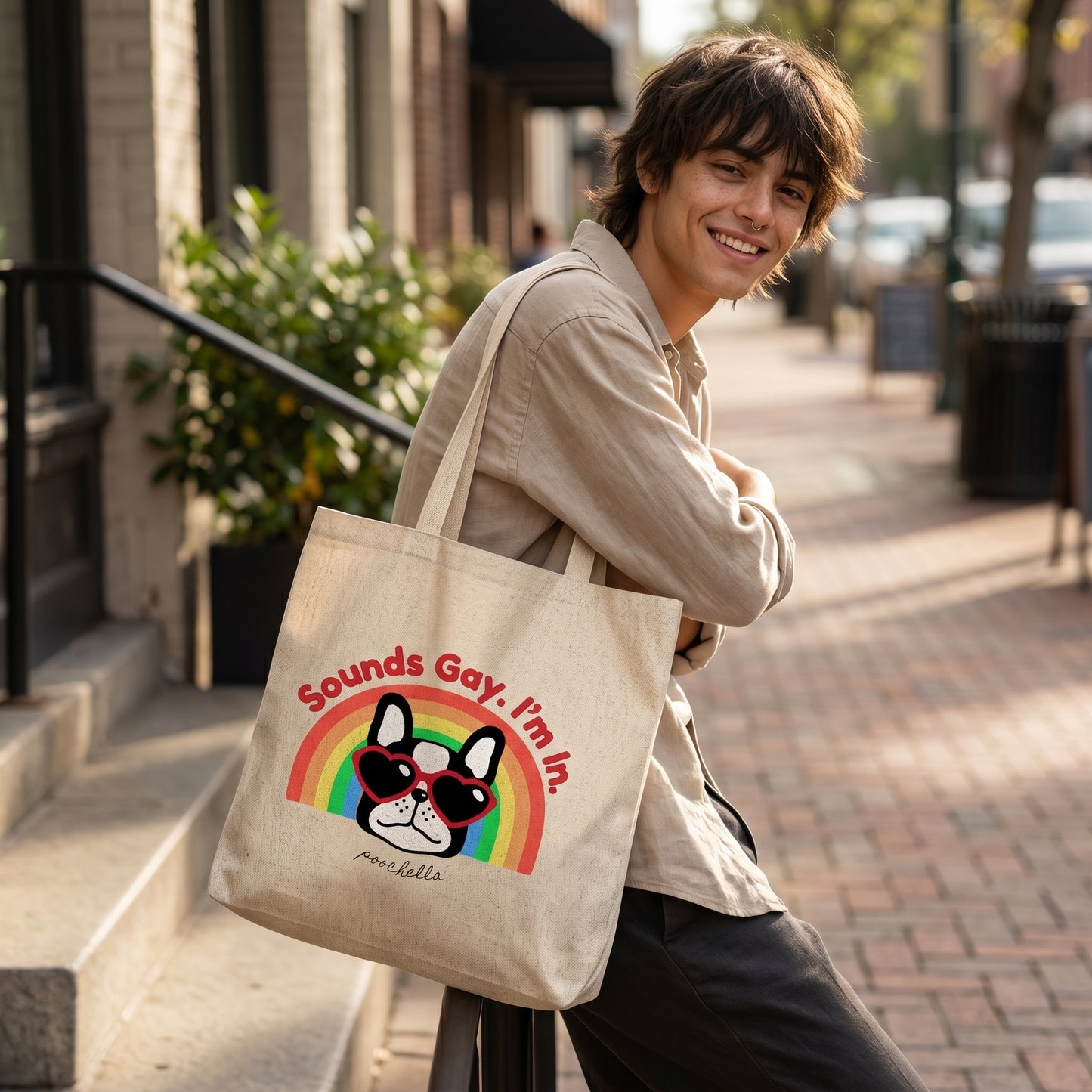 Person holding a tote bag with a dog graphic and text on a city street.
