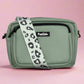 Green bag with a leopard print strap on a pink background