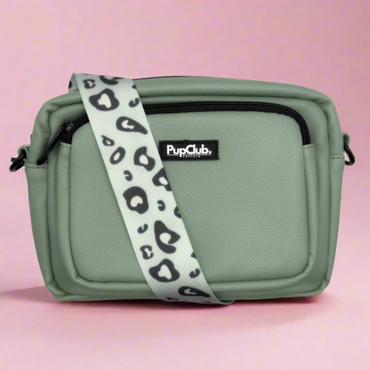 Green bag with a leopard print strap on a pink background