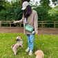 Person with a green bag and two dogs in a park setting