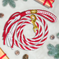 Red and white rope dog leash with gold clasp on a light gray background with Christmas decorations.