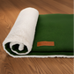 Green and white textured blanket with a brand label on a wood background