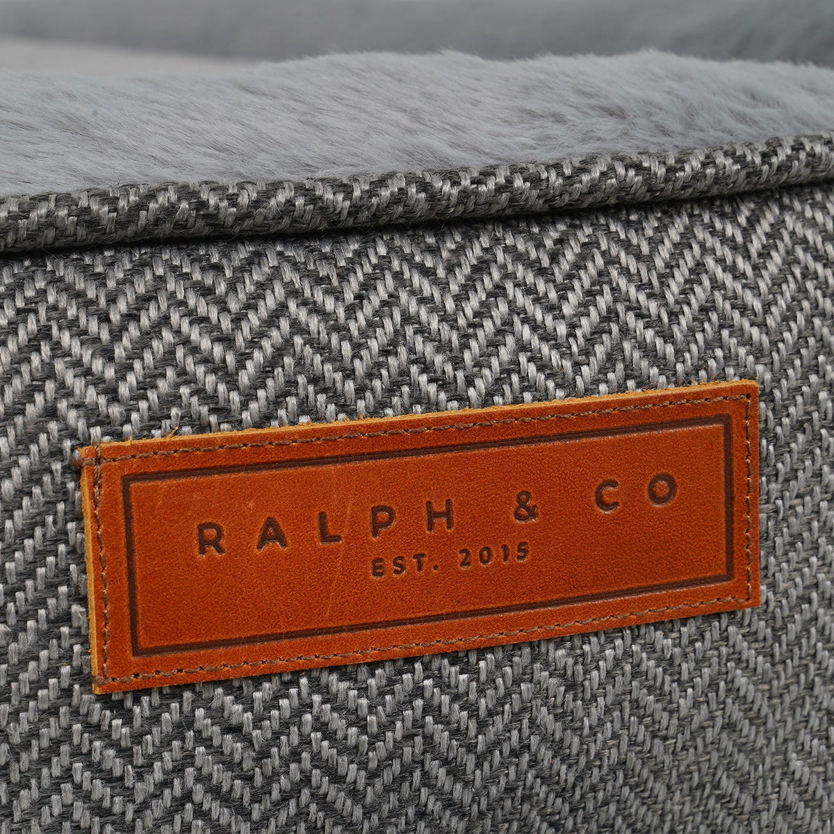 Gray textured fabric with a brown leather label reading 'RALPH & CO EST. 2015'.