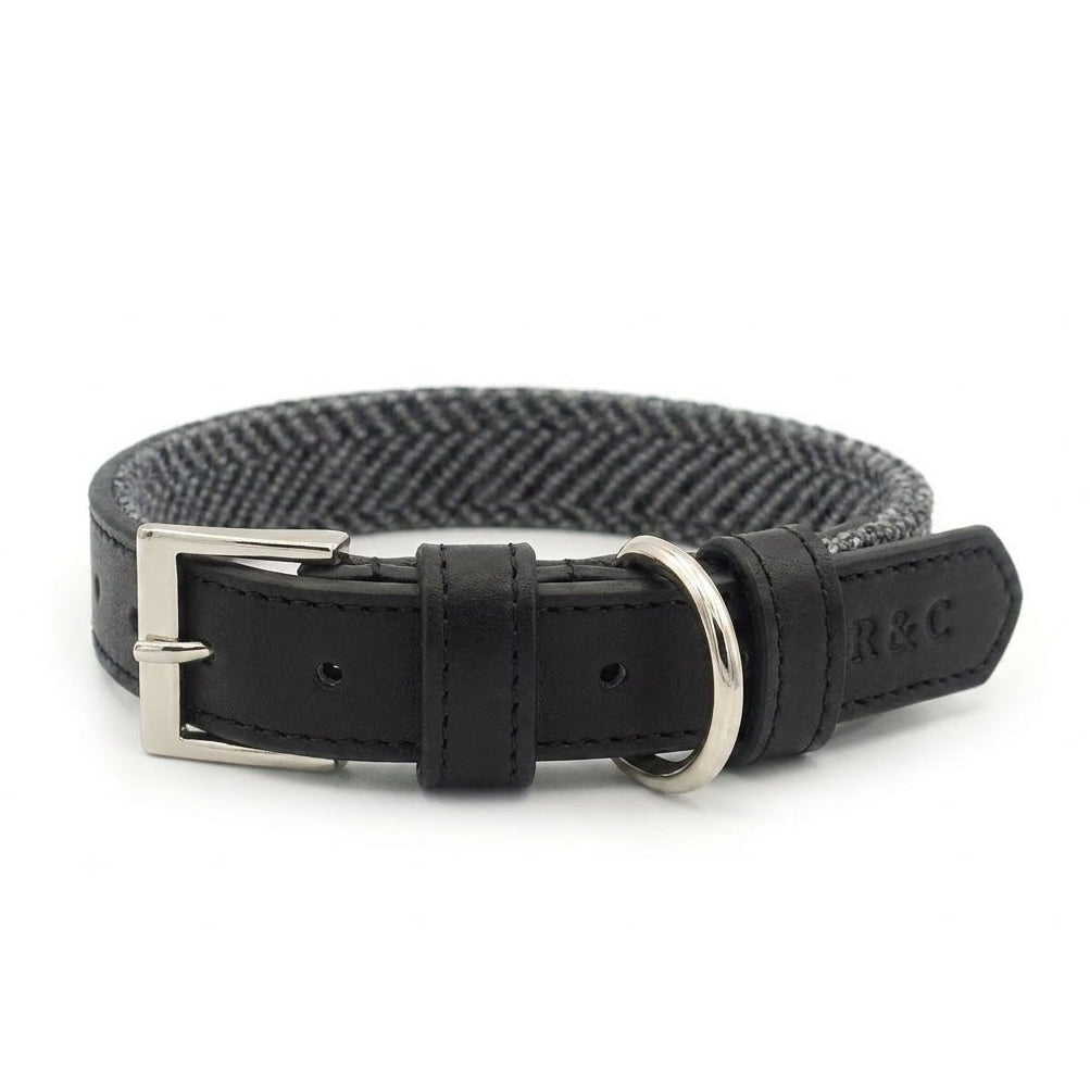 A black leather dog collar with a silver-tone buckle, a silver-tone D-ring, and a black and gray herringbone patterned fabric inner lining. The brand name 'R&C' is embossed on the leather keeper.
