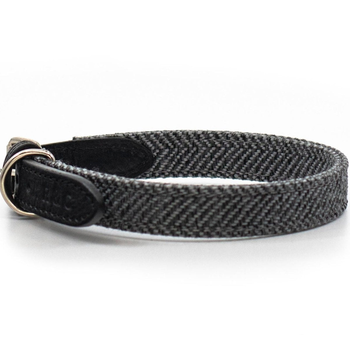 A black and gray herringbone woven dog collar with a black leather buckle and silver metal ring, shown on a white background.