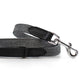 Gray herringbone and black leather dog lead on a white background