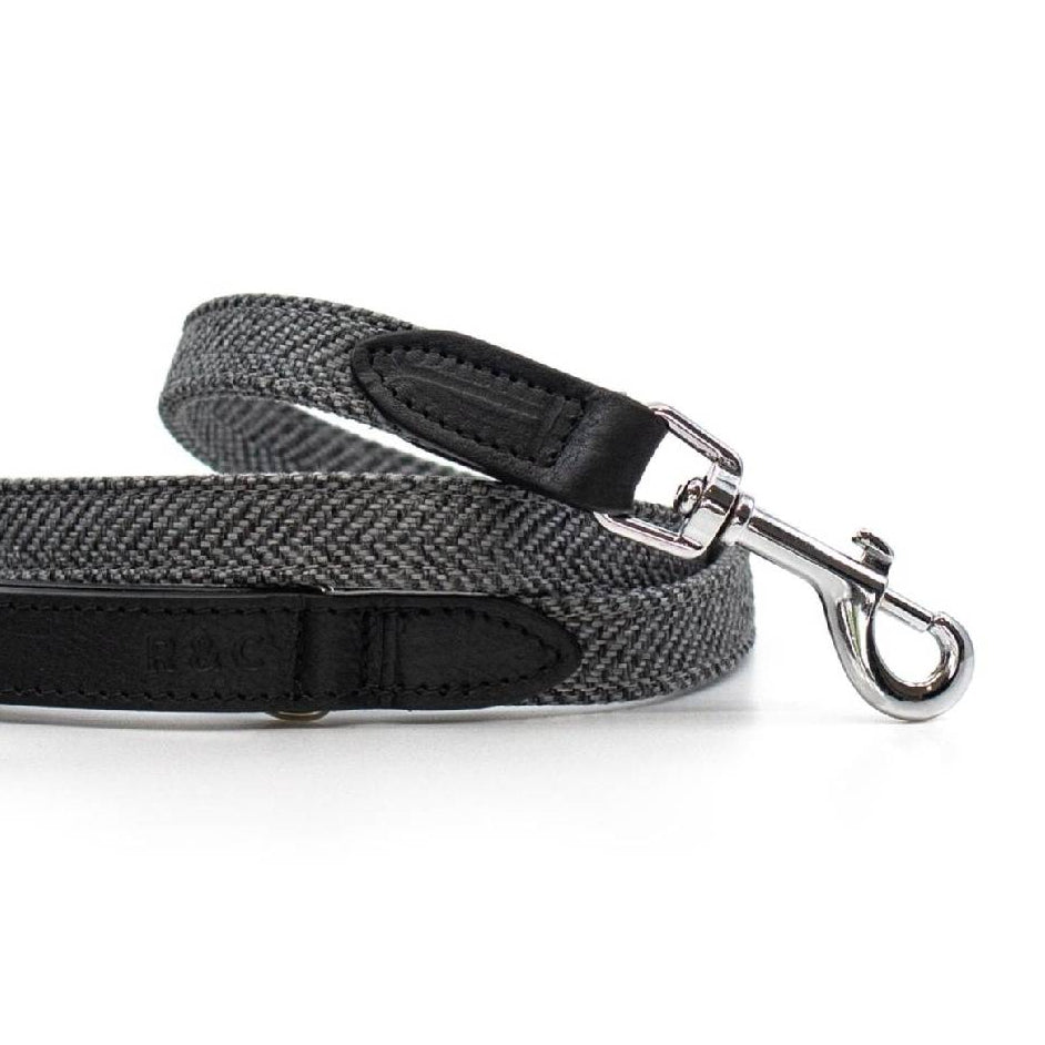 Gray herringbone and black leather dog lead on a white background