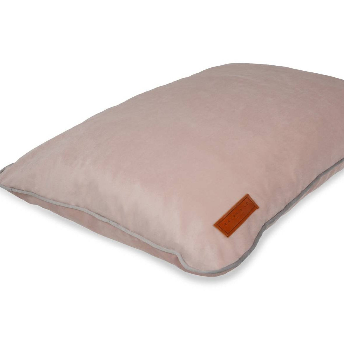 Pink dog crate pillow with a brown label on a white background