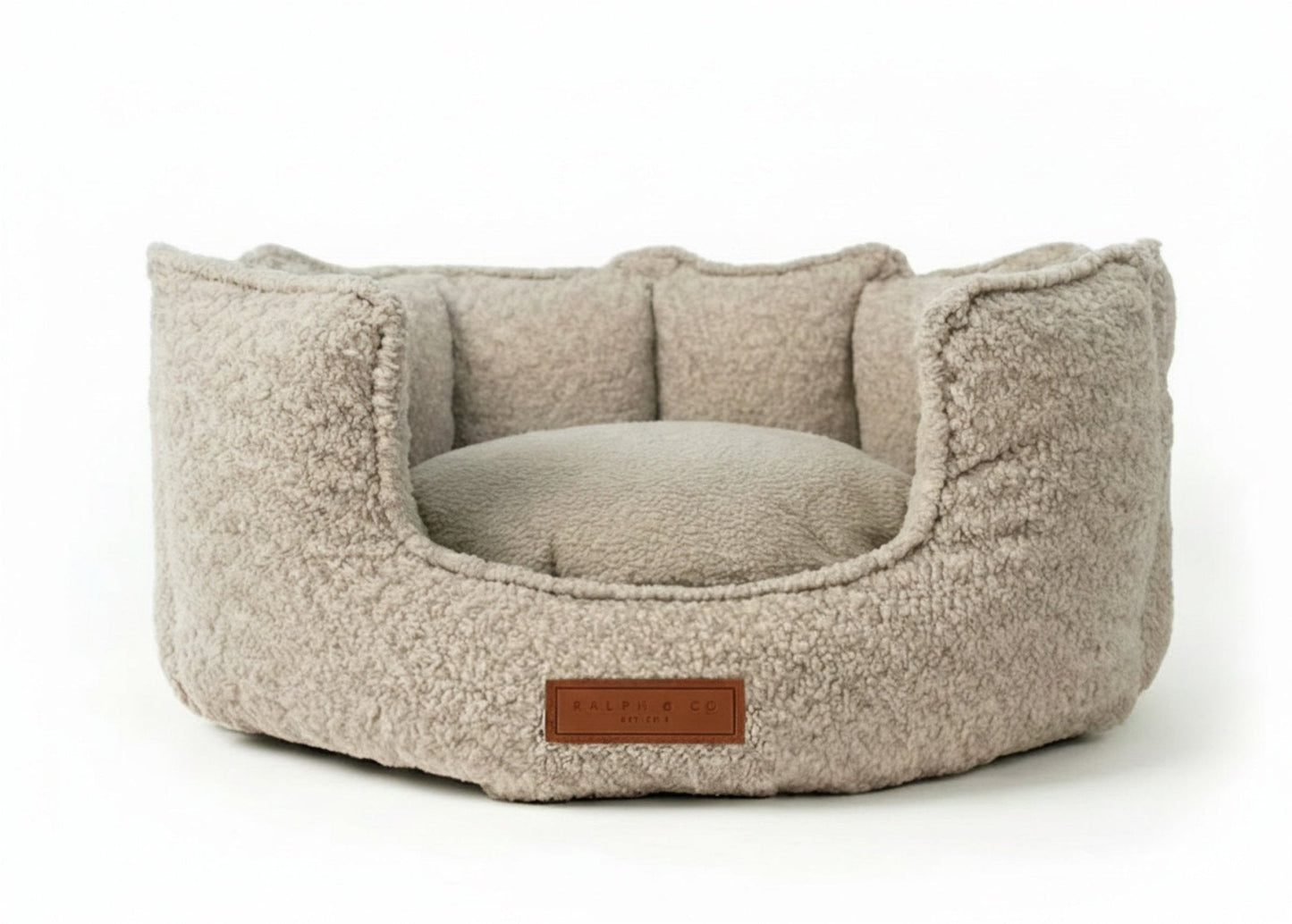 Beige pet bed with a brown label on a white background