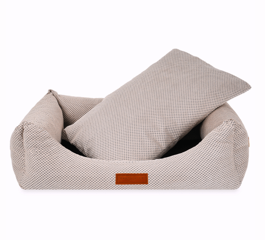 Beige pet bed with a pillow on a white background
