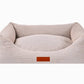 Beige pet bed with a brown label on a white background