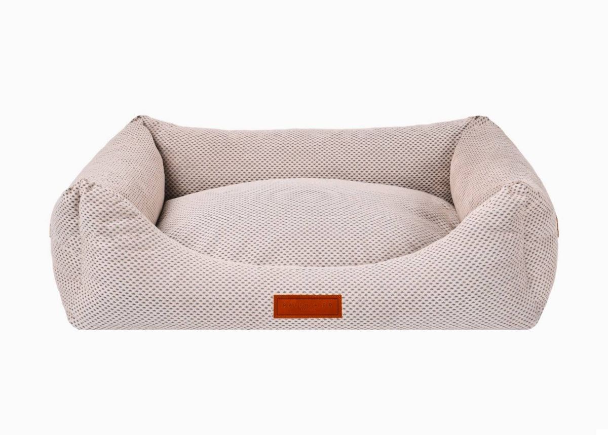 Beige pet bed with a brown label on a white background