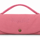 A pink  handbag with a top handle, featuring the brand name 'Hugo & Ted' embroidered on the front flap and a gold snap button closure, set against a plain white background.