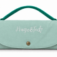 A mint green nylon handbag with a top handle, featuring the embroidered text 'Hugo&Ted' on the front flap and a gold snap button closure, set against a plain white background.