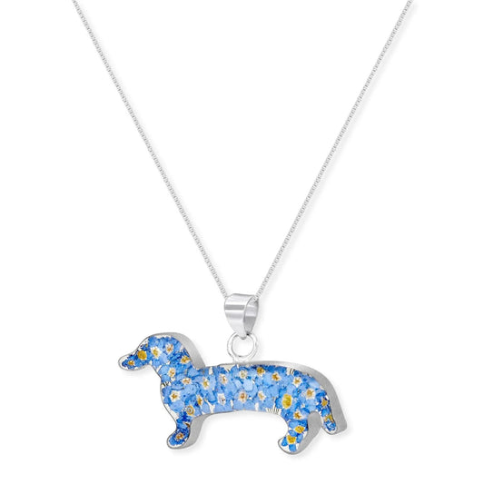 A silver dachshund-shaped pendant necklace filled with small blue flowers and yellow centers, hanging from a delicate silver chain against a plain white background.