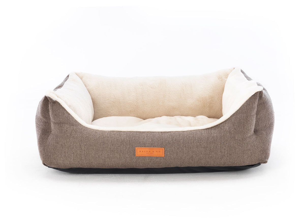 Dog bed with beige fabric and white interior on a white background