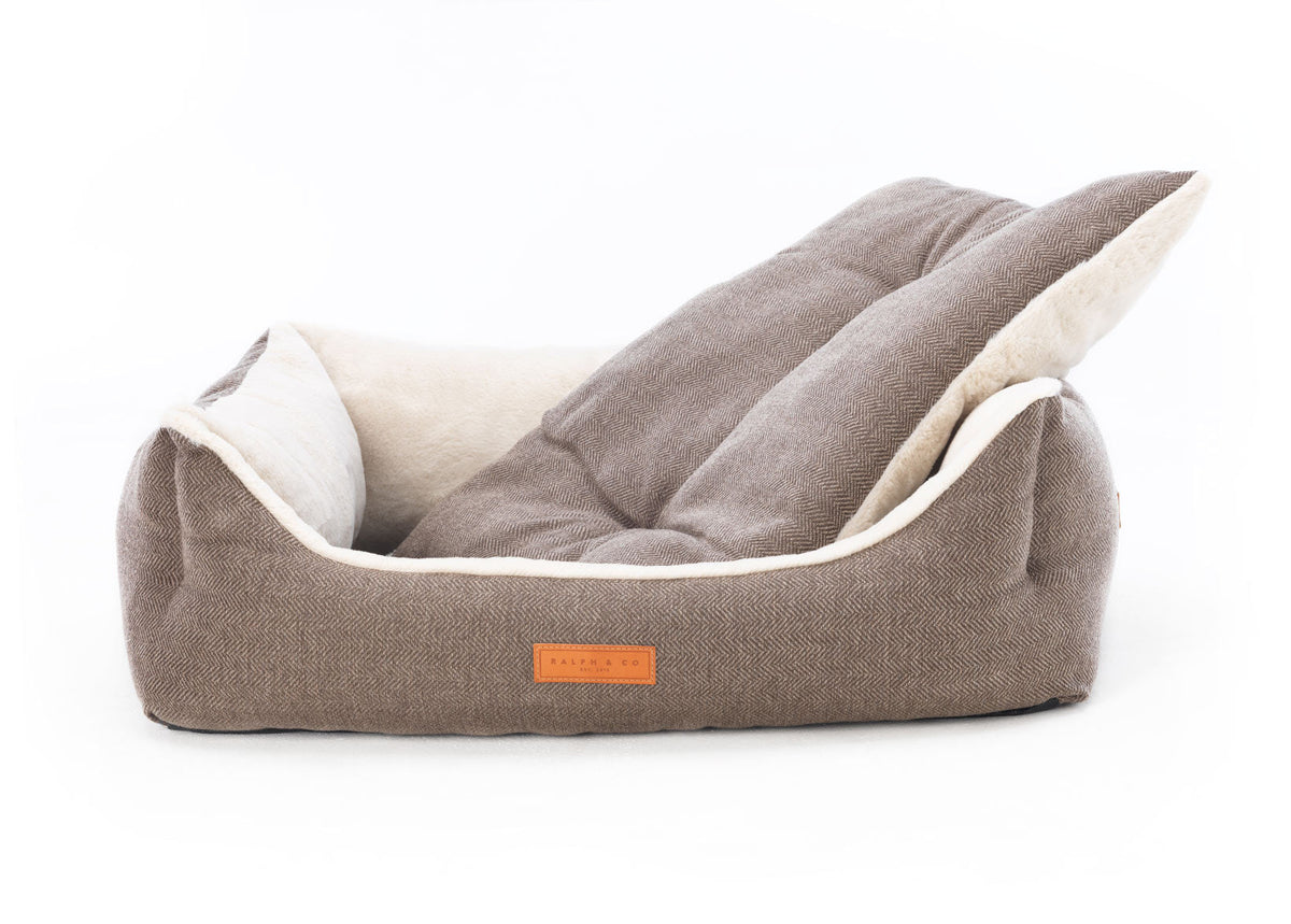 Pet bed with a brown exterior and white interior on a white background