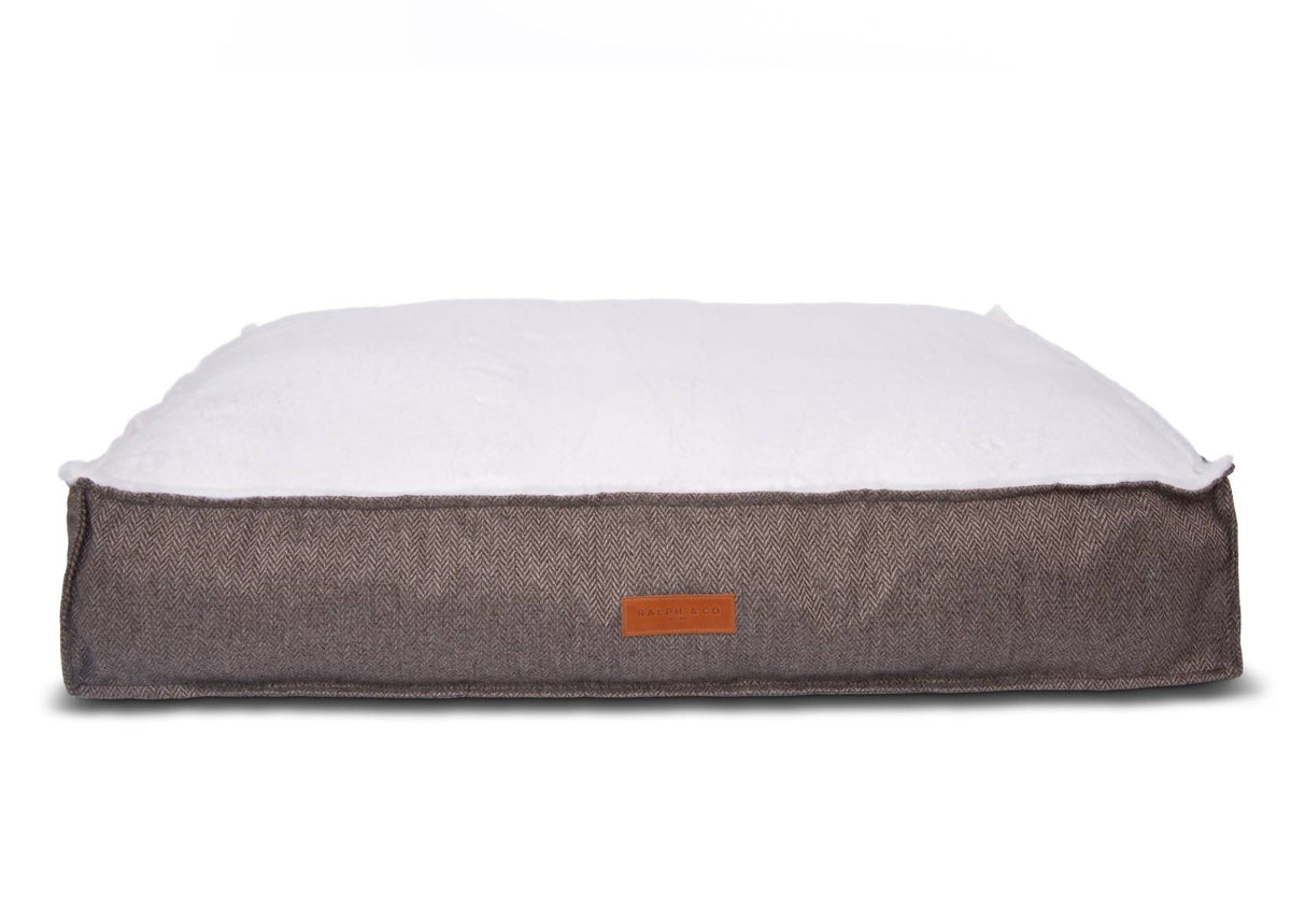 Dog bed with brown tweed fabric exterior and white cushion on a white background
